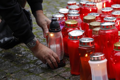 Ljudje prižigajo sveče v spomin moškega ki je umrl pred lokalom patriot