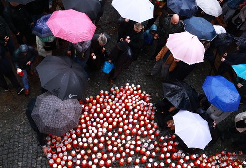 Ljudje prižigajo sveče v spomin moškega ki je umrl pred lokalom Lokalpatriot