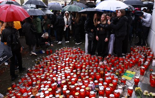 Ljudje prižigajo sveče v spomin moškega ki je umrl pred lokalom Lokalpatriot