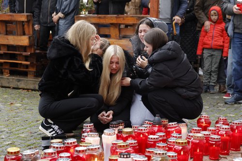 Ljudje prižigajo sveče v spomin moškega ki je umrl pred lokalom patriot