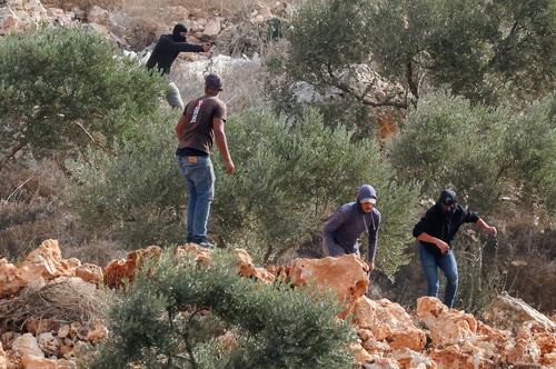 An Israeli settler points a gun amid clashes with Palestinians harvesting olives in Abu Falah near Ramallah in the Israeli-occupied West Bank, October 16, 2026. REUTERS/Ammar Awad TPX IMAGES OF THE DAY