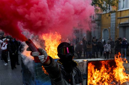 A protester wearing a mask holds a flare next to a burning barricade during an anti-government protest in Tirana, Albania, October 31, 2026. REUTERS/Florion Goga