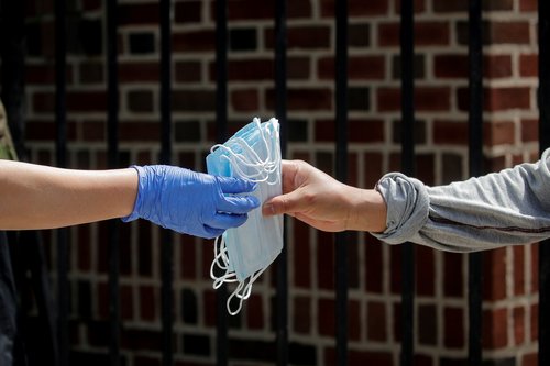 FILE PHOTO: A woman receives protective face masks while she waits in line at a food bank at St. Bartholomew Church