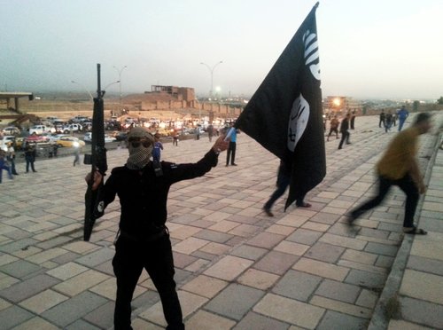 FILE PHOTO: A fighter of the ISIL holds a flag and a weapon on a street in Mosul