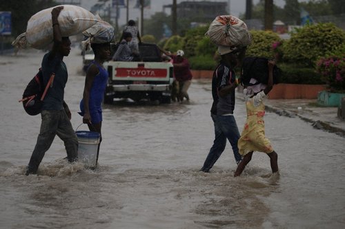 FILE PHOTO: People cross a flooded street during the passage of Tropical Storm Laura, in Port-au-Prince