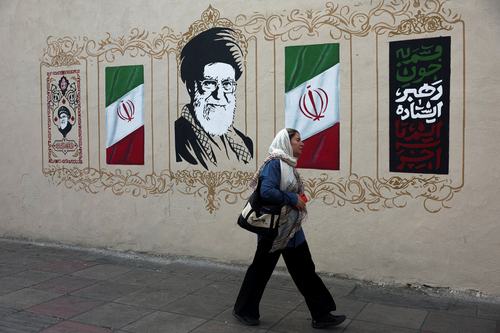 Iranka hodi mimo portreta pokojnega vrhovnega voditelja Alija Hameneja v Teheranu
