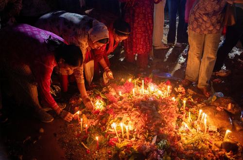 Ljudje prižigajo sveče pri skupni grobnici žrtev poplav v Nepalu