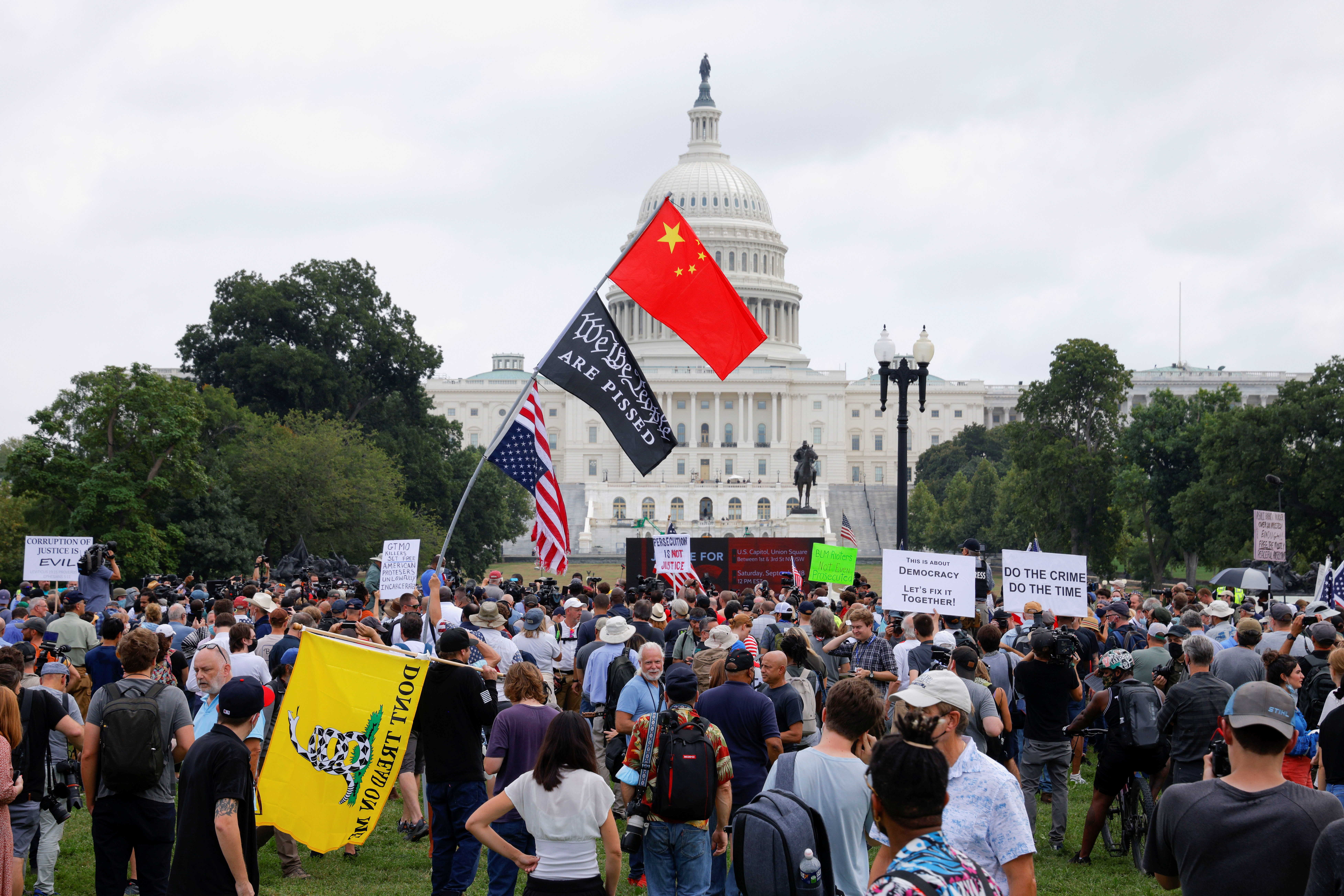 People hold signs as they gather in front of the U.S. Capitol during a rally in support of defendants being prosecuted in the January 6 attack on the Capitol, in Washington