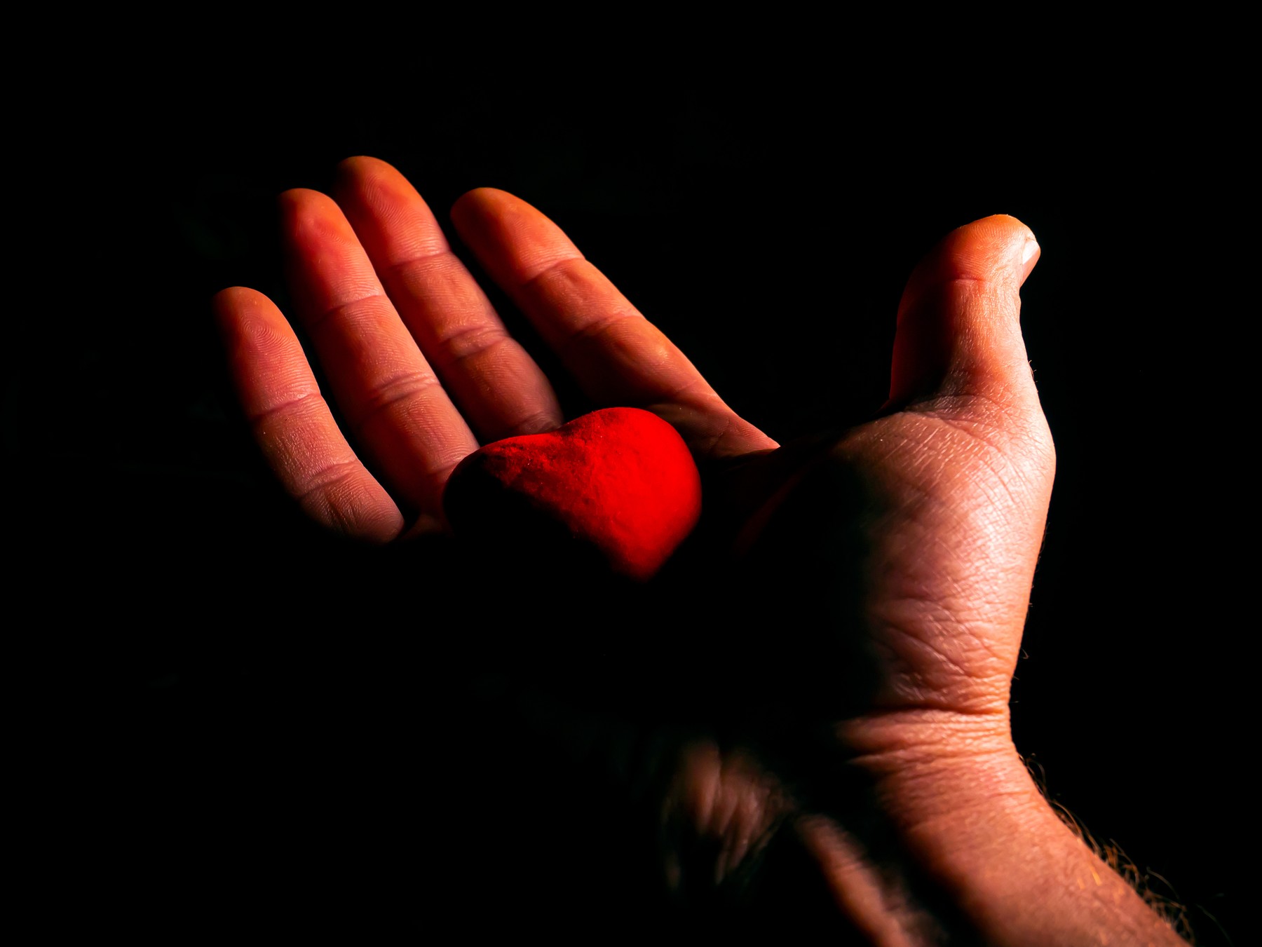 Heart symbol of valentines day in hand on black background.