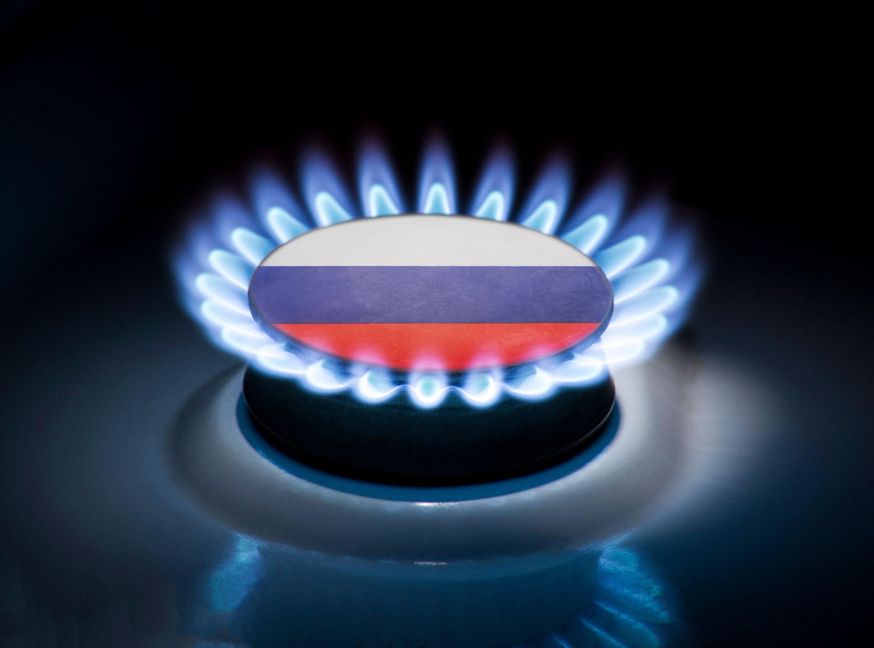 Burning gas burner of a home stove in the middle of which is the flag of the country of Russia. Gas import and export delivery concept, price per cubi