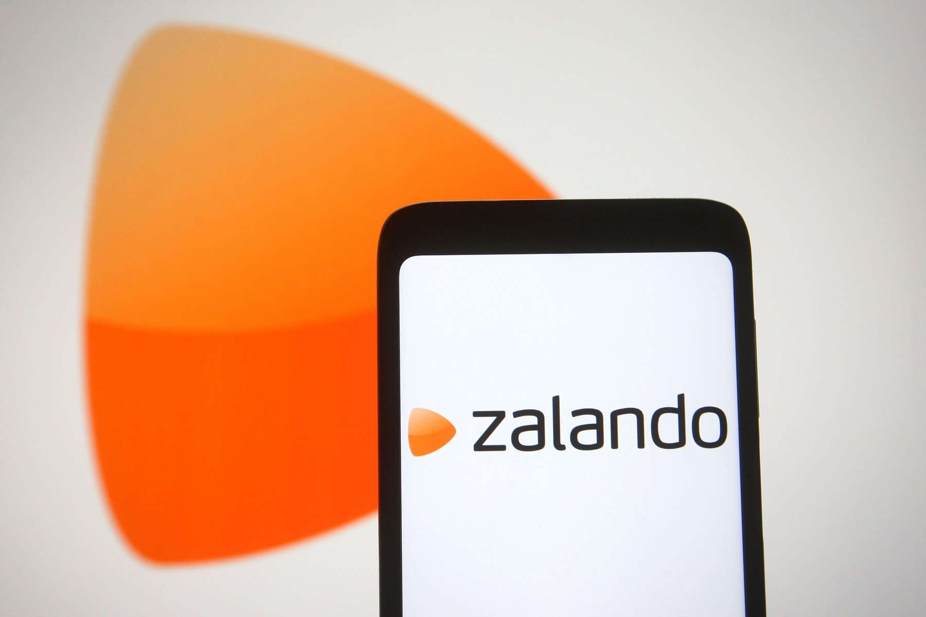 In this photo illustration a Zalando logo of a European e-commerce company is seen on a smartphone and a pc screen.