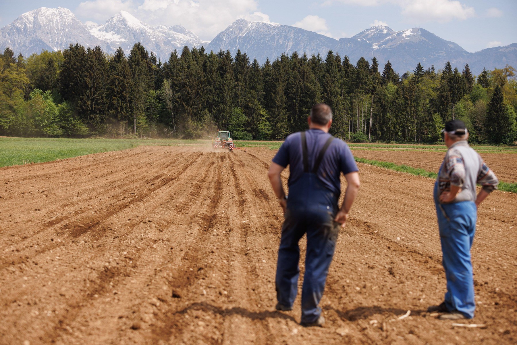 Farmers stand on a field as a tractor plants sweet corn in Hrastje near Kranj. With the arrival of spring, farmers begin planting sweet corn, while the global food crisis looms around the corner. According to farmers, Slovenia could easily be self-suffici