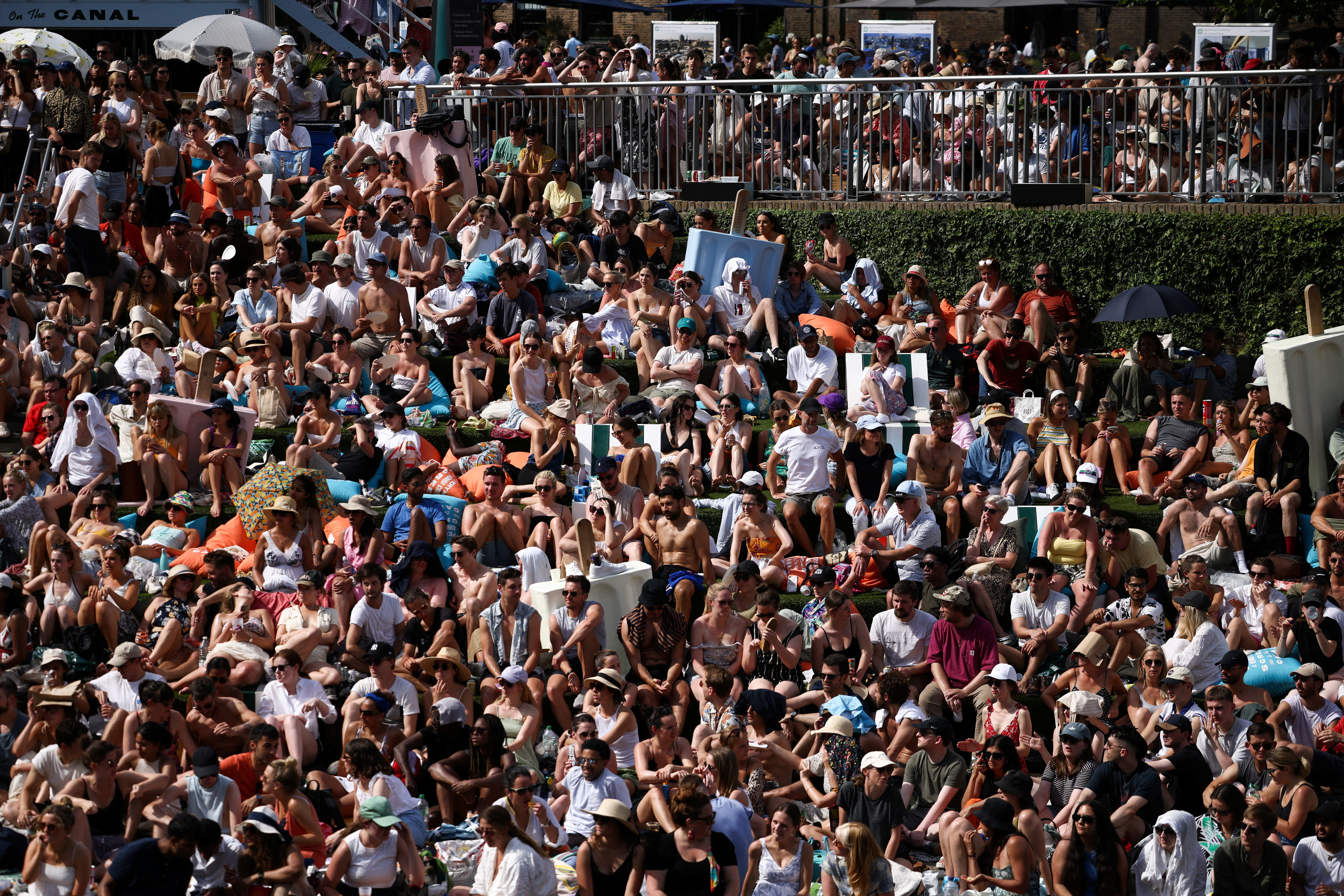 People watch the Wimbledon men’s singles final tennis match on a giant screen next to the Regent’s canal at Granary Square, during hot weather in London