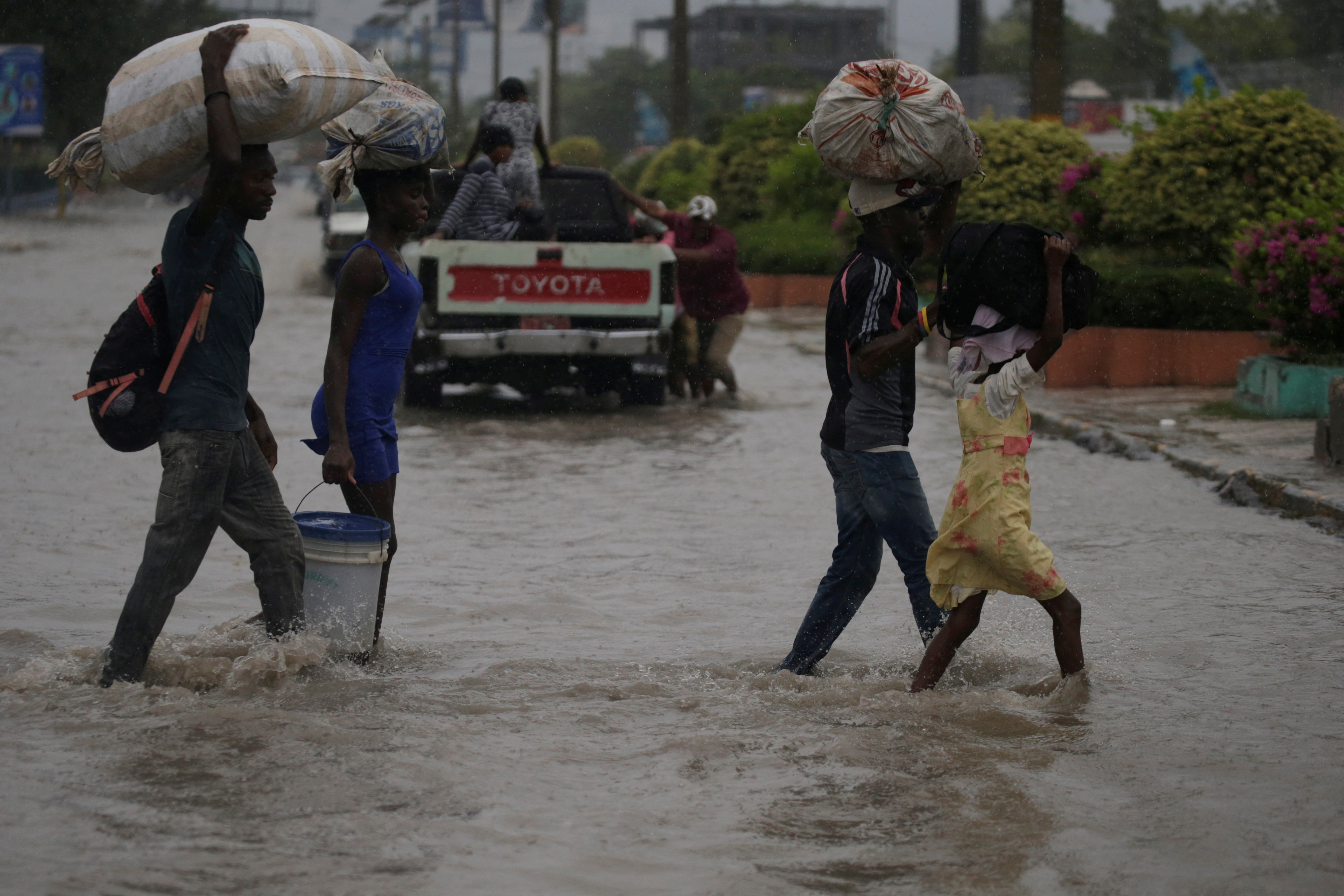 FILE PHOTO: People cross a flooded street during the passage of Tropical Storm Laura, in Port-au-Prince
