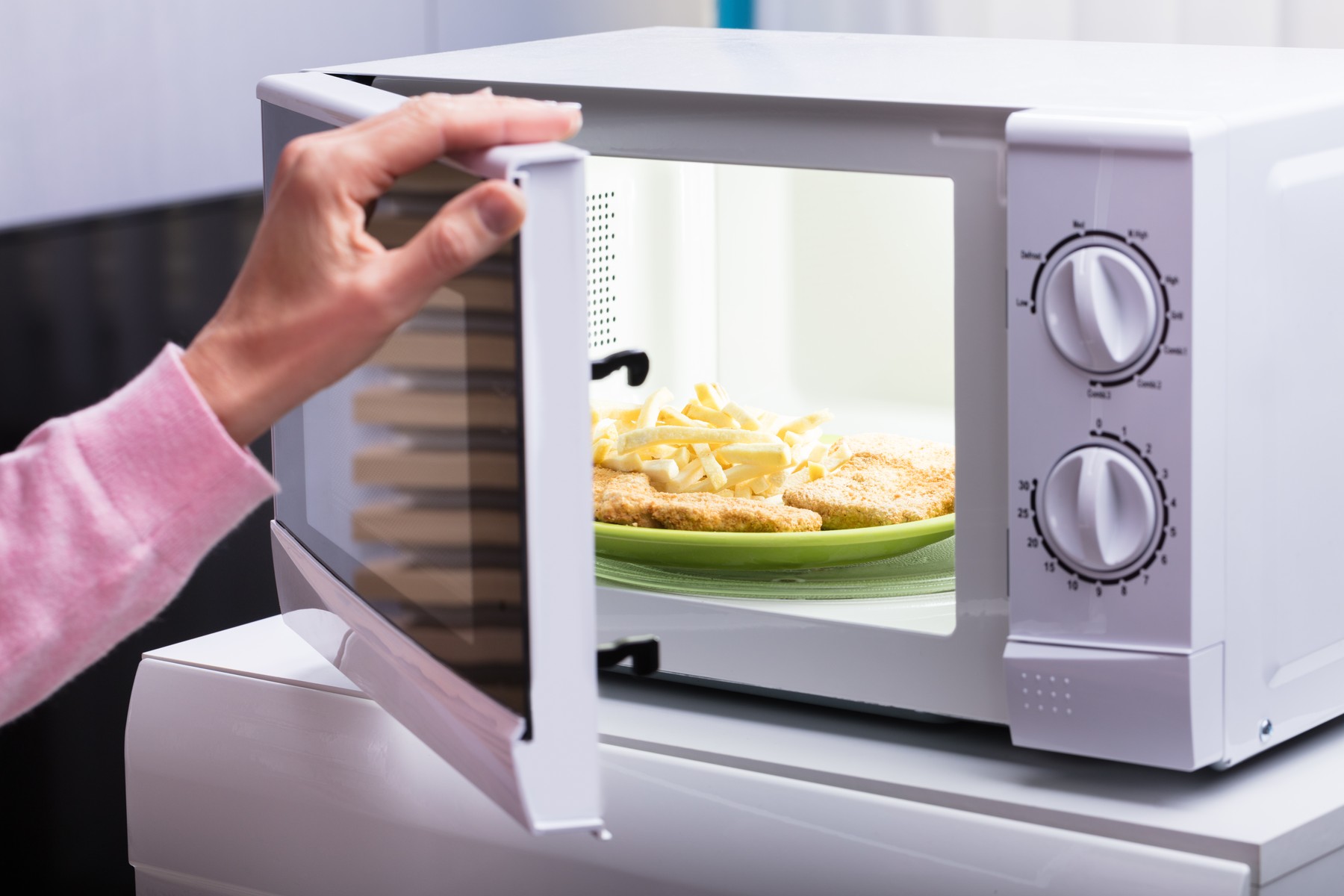 Woman Heating Fried Food In Microwave Oven