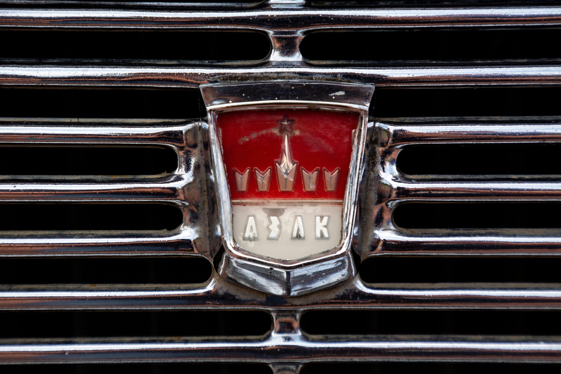 Closeup view of an emblem of the AZLK soviet automobile brand on a radiator of the Moskvich car