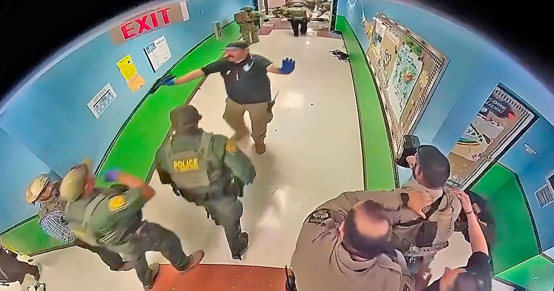 A frame from a school surveillance video shows multiple police officers waiting in a hallway at Robb Elementary School armed with rifles and at least one protective ballistic shield. This was 19 minutes after receiving a 911 call from the school. The poli