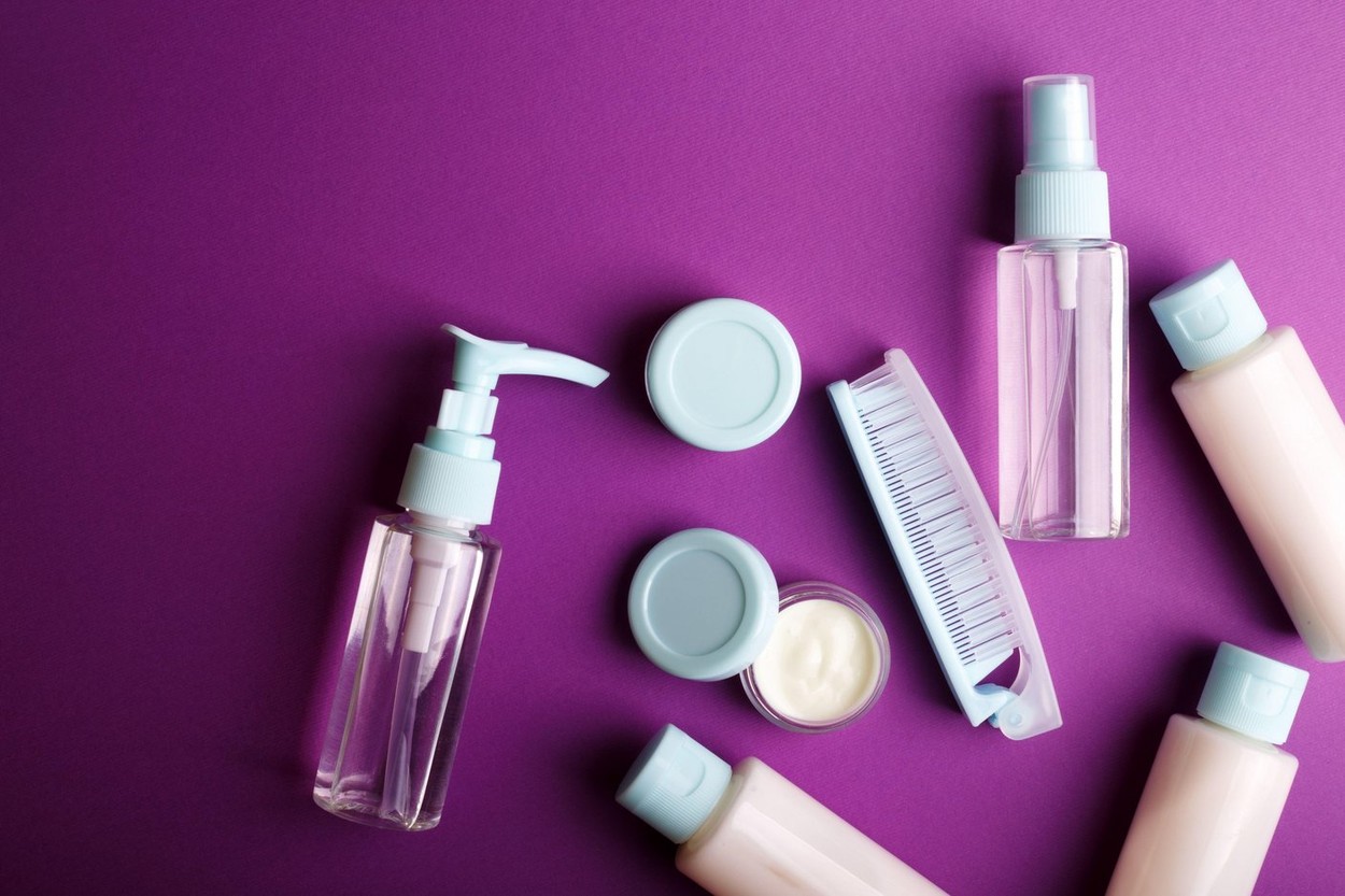 travel beauty kit on a purple background. shampoo, balm, cream and lotion in vials