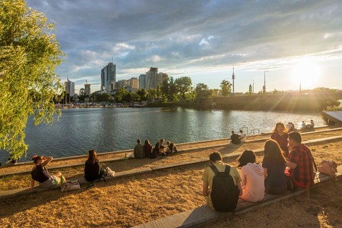 Wien, Vienna: late sun at river Alte Donau (Old Danube), people watch sunset, boats, tower Donauturm, highrises of Donaucity, DC Tower 1 in 22. Donaus