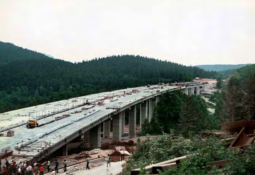 neznan, vir: arhiv DARS d. d. | Ogled gradnje voziščne plošče viadukta Ravbarkomanda na avtocestnem
odseku med Uncem in Postojno. Voziščna plošča je sestavljena iz
posameznih montažnih plošč, ki so z armaturo in betonom skupaj z
vzdolžnimi 'I' nosilci povezane v enovito konstrukcijo. 