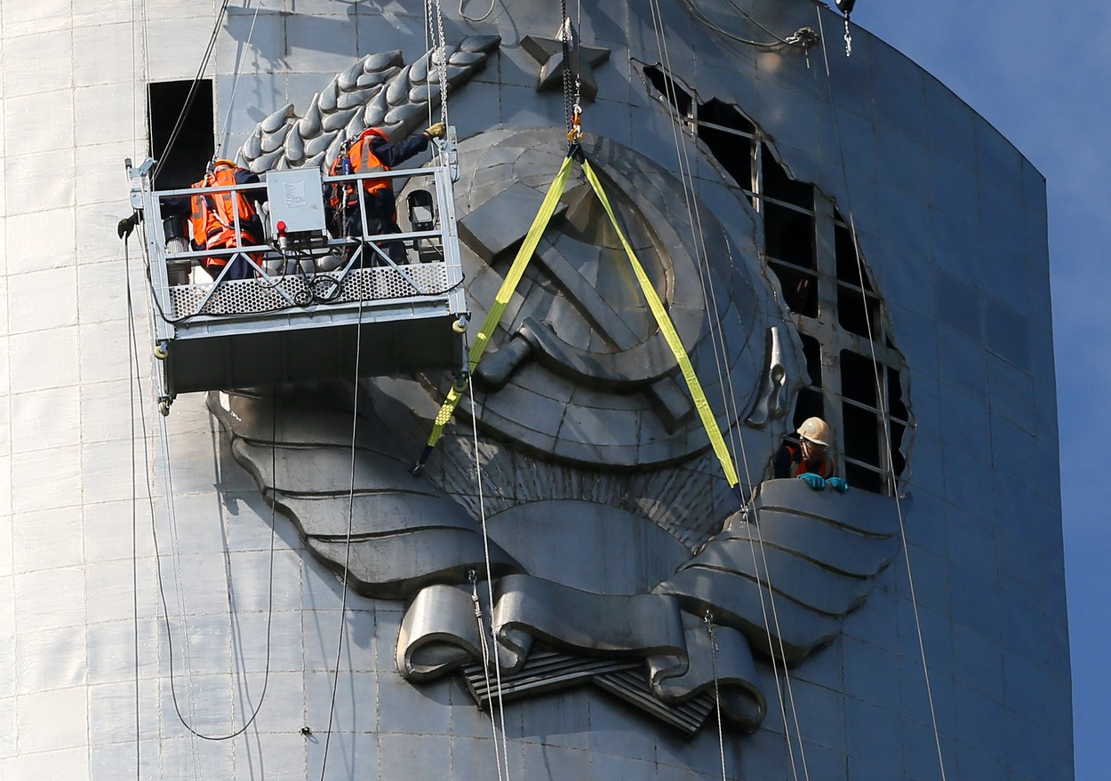 Workers remove the Soviet coat of arms from the shield of the Motherland Monument in Kyiv