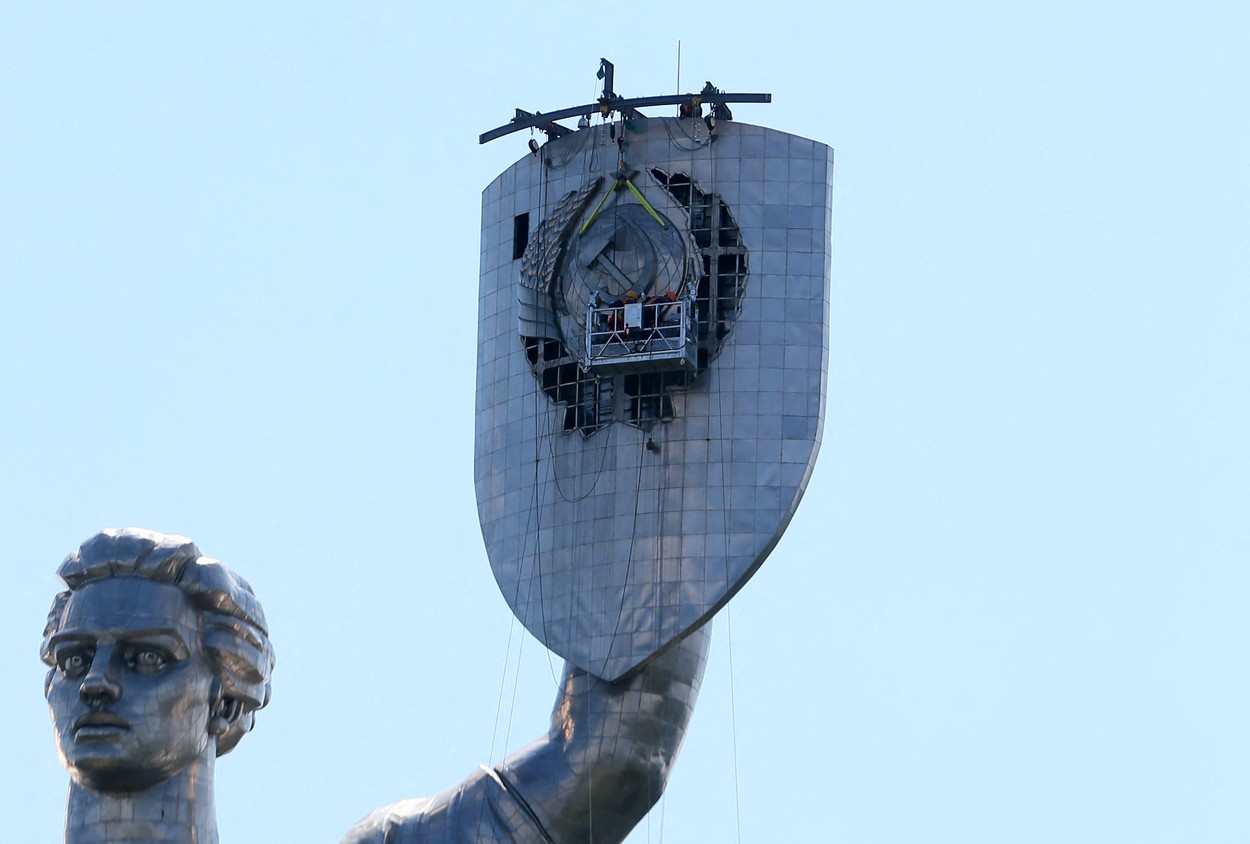 Workers remove the Soviet coat of arms from the shield of the Motherland Monument in Kyiv