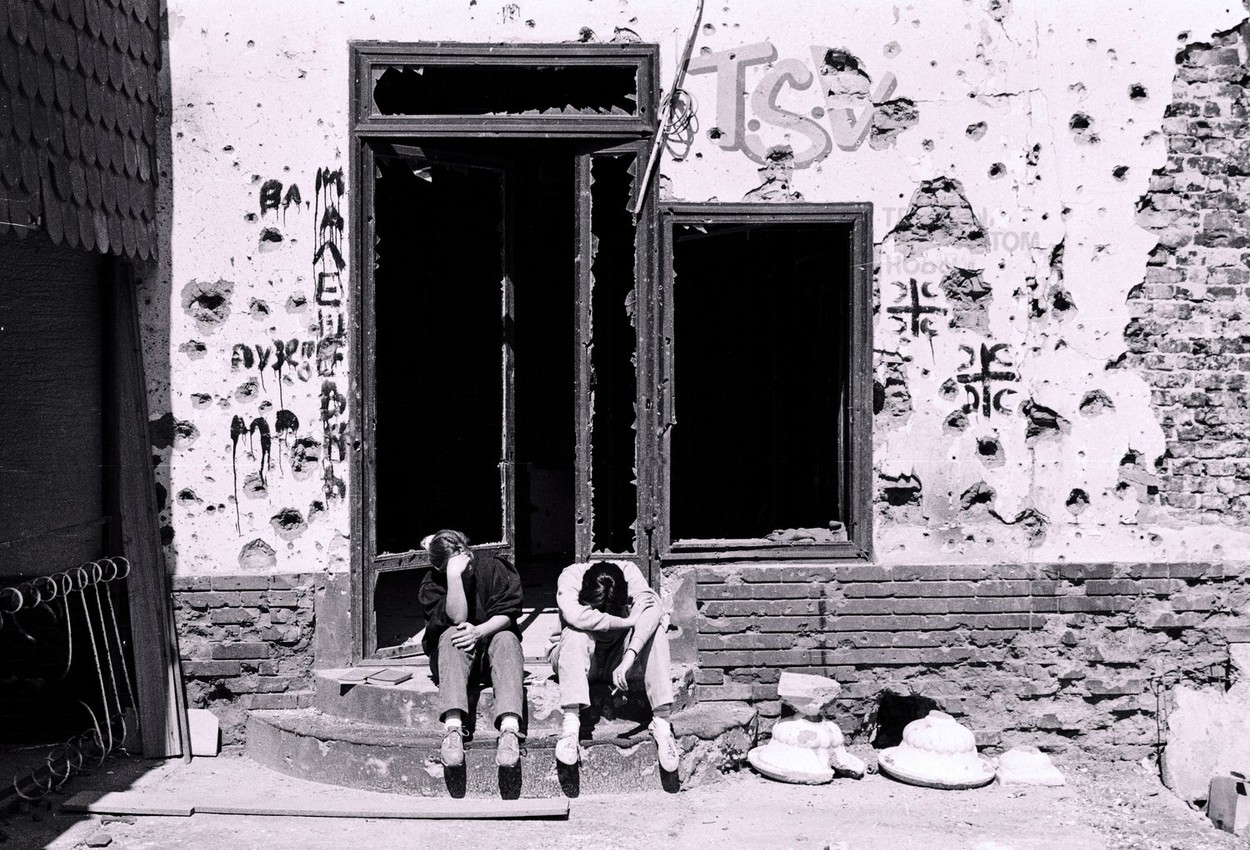 Two girls bow their heads while crying outside a ruined storefront in Vukovar, Croatia, on Saturday, November 2, 1991.