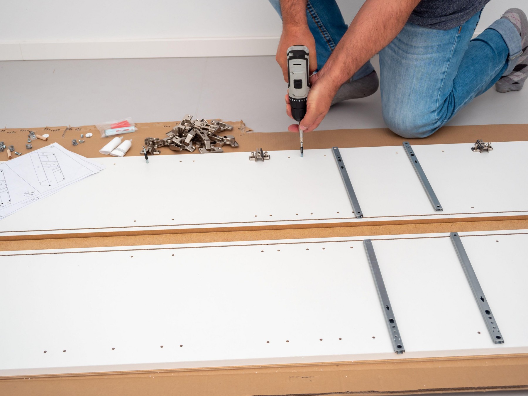 A man assembles furniture at home with a professional screwdriver. Furniture assembly.