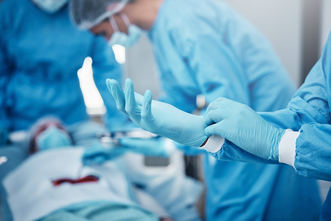 Hospital, surgery and doctors in team with gloves, ppe and safety to help patient on bed with stomach cancer. Doctor tea