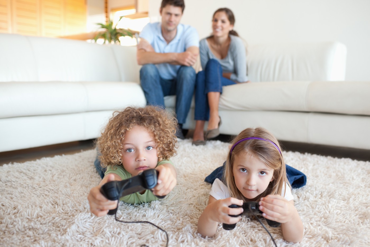 Cute children playing video games while their parents are watching