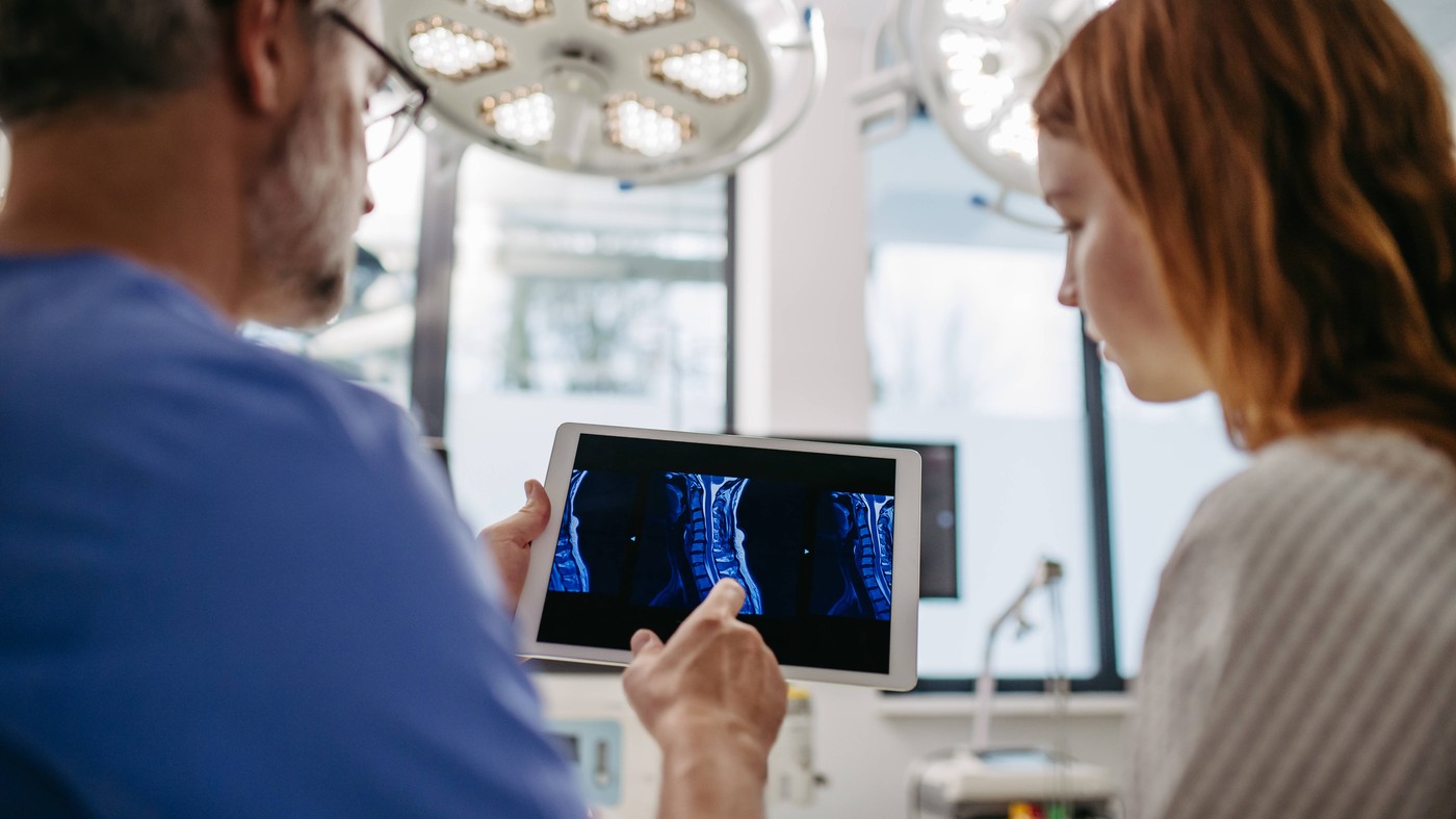 Doctor discussing test resulst with teenage patient, showing data on tablet in emergency room. Doctor discussing test re