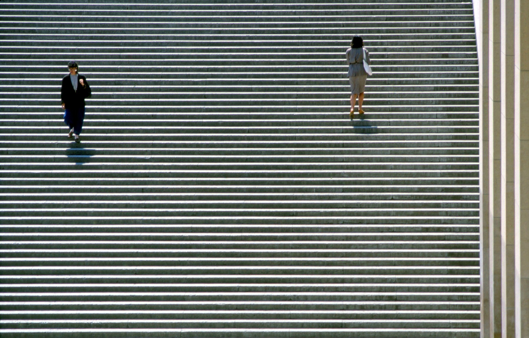 Two women walking up and down stairs.