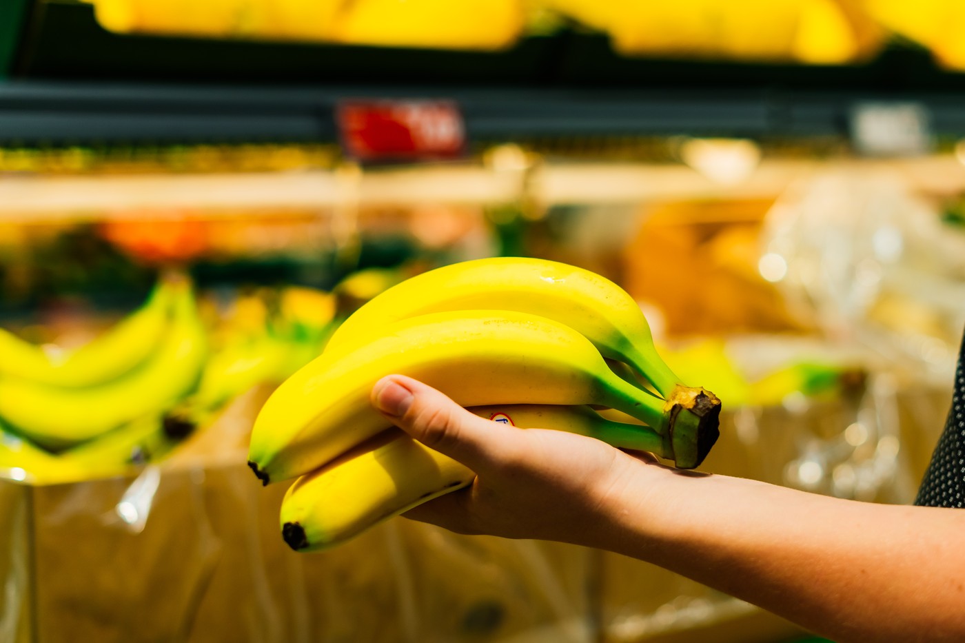 Boy holding a bunch of bananas in the supermarket
