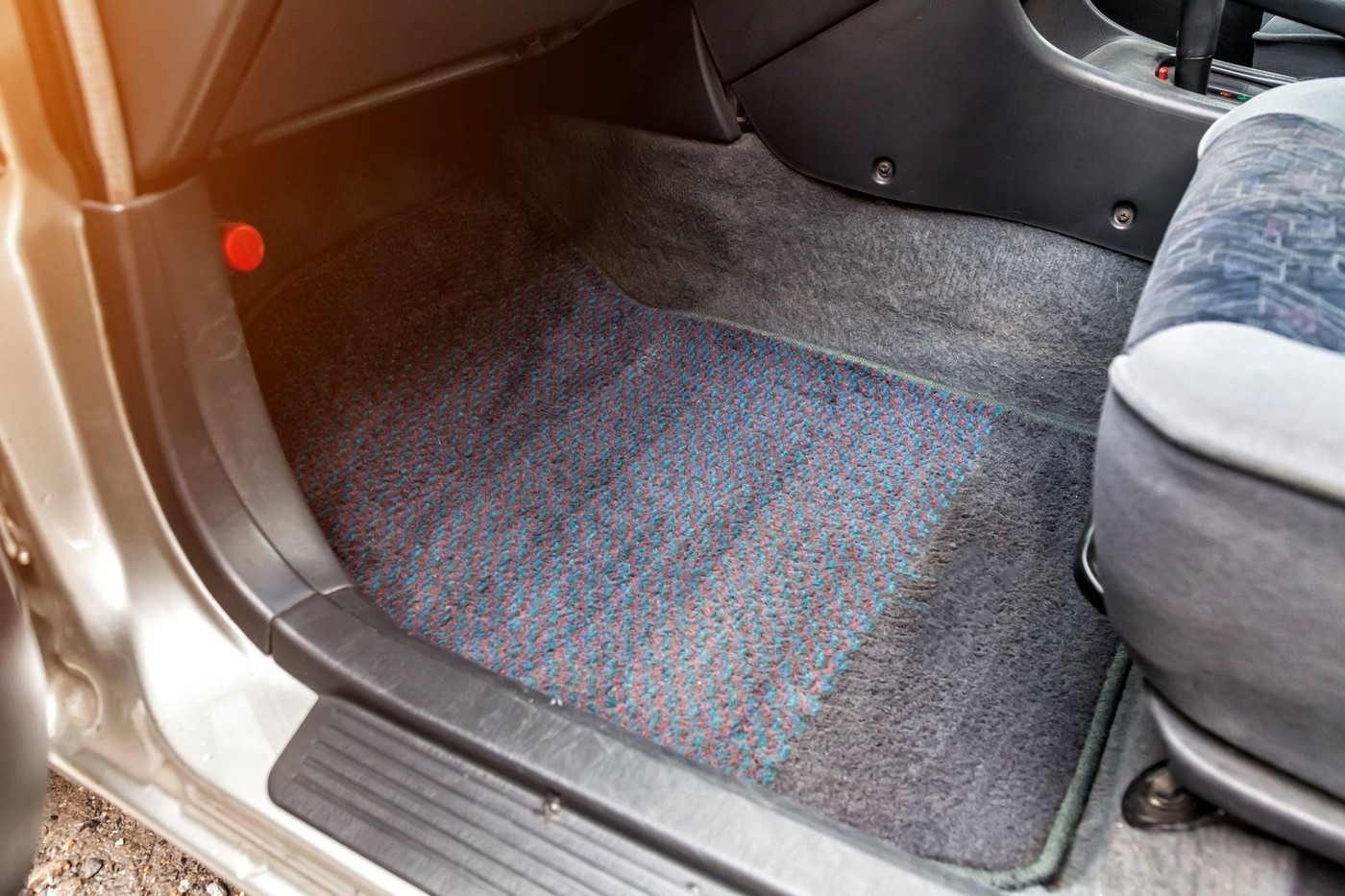 The car mat under the front passenger seat is made of gray textile material in service after a dry cleaning of the passenger compartment close-up duri