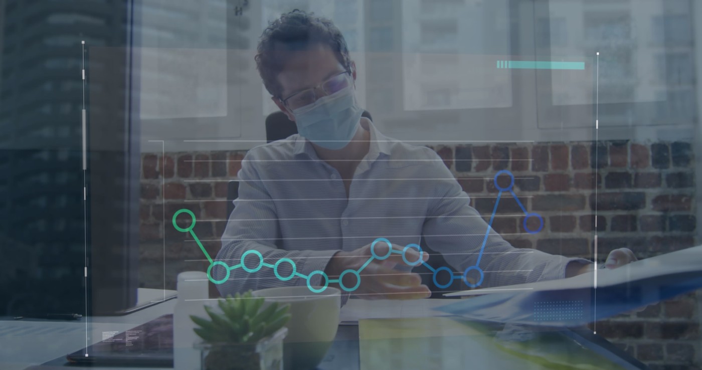 Image of graph over caucasian male doctor wearing mask analyzing reports on desk in hospital