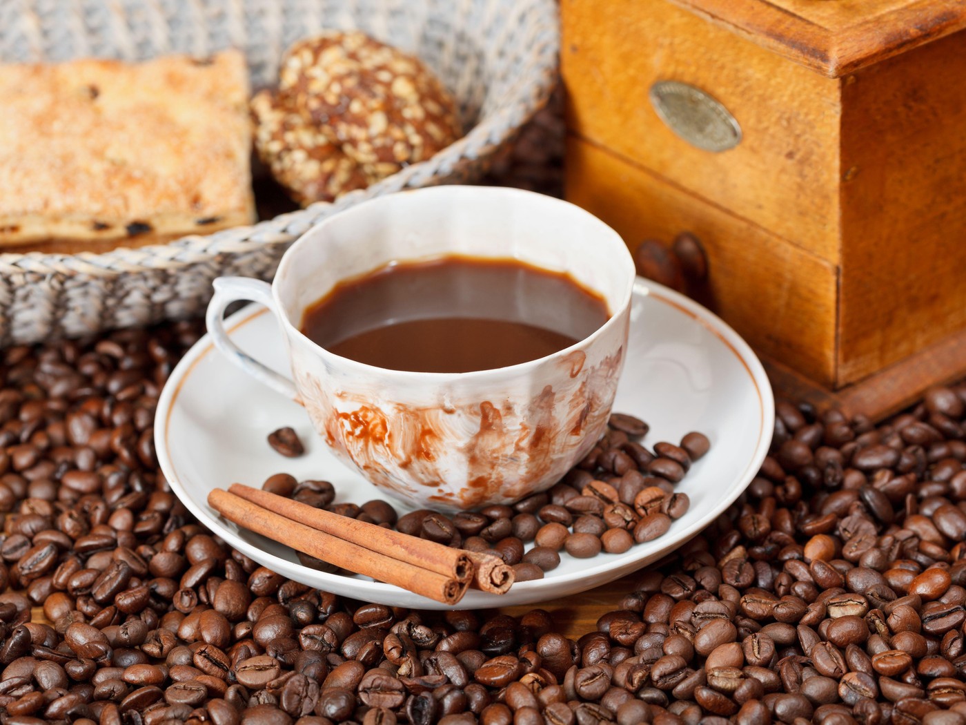 cup of coffee and roasted coffee beans with retro wooden manual mill, biscuit, cinnamon