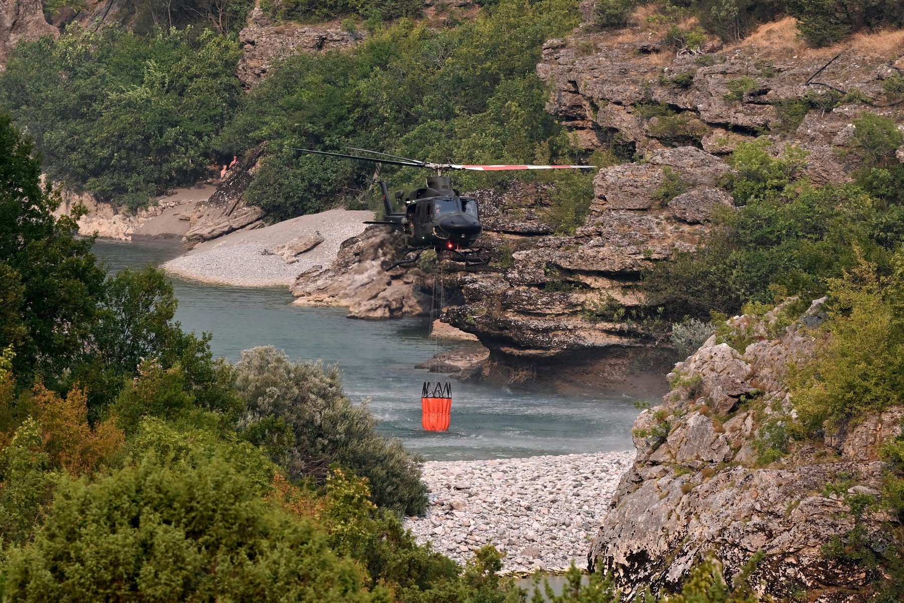 A Montenegrin Bell 412 army helicopter collects water as it fights against a wildfire raging on the outskirts of the Podgorica capital, on August 13, 2025.,Image: 1029232959, License: Rights-managed, Restrictions: , Model Release: no