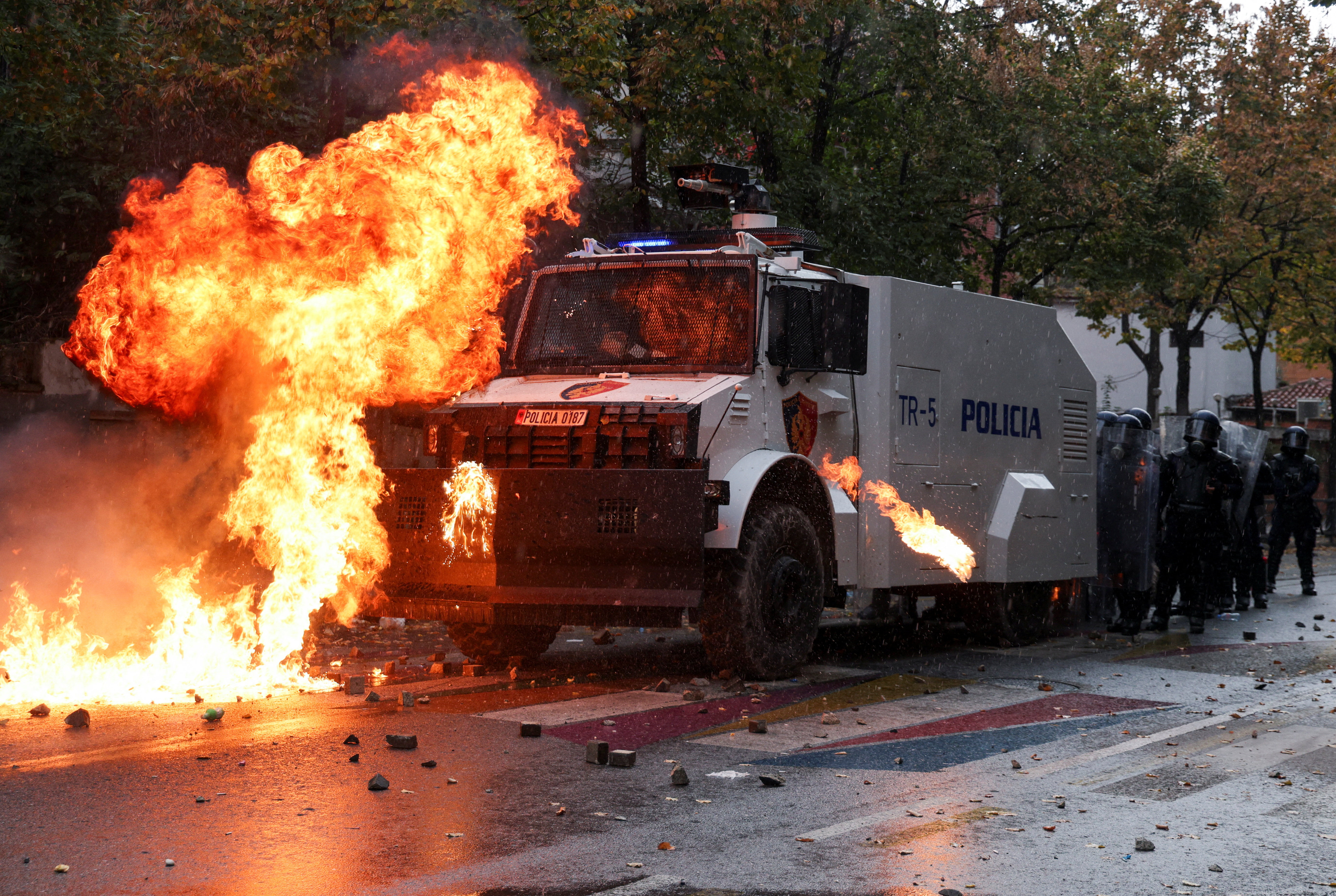 Flames rise after the impact of a petrol bomb next to police water cannon truck and officers in riot gear, during an anti-government protest in Tirana, Albania, October 31, 2026. REUTERS/Florion Goga