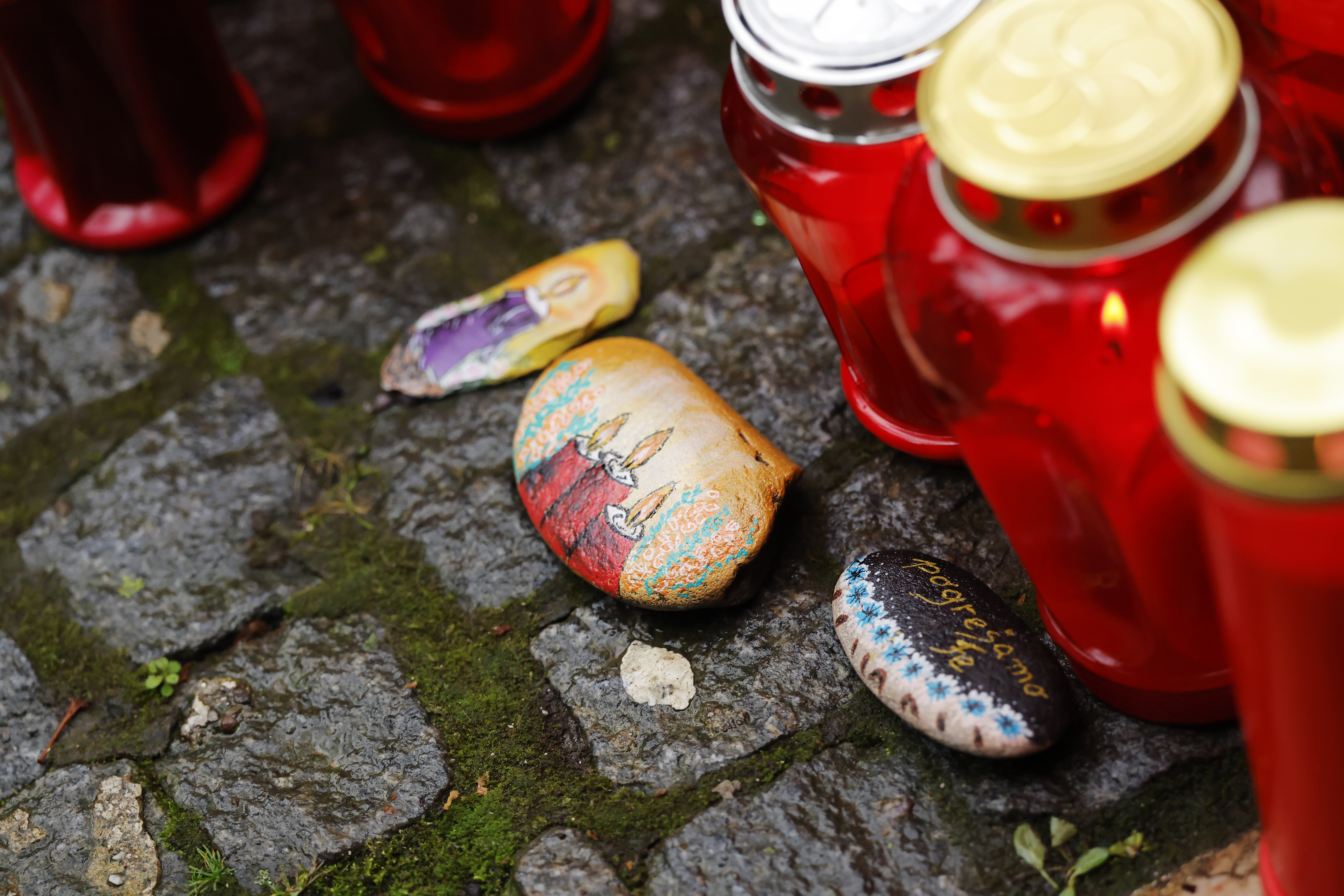 Ljudje prižigajo sveče v spomin moškega ki je umrl pred lokalom Lokalpatriot