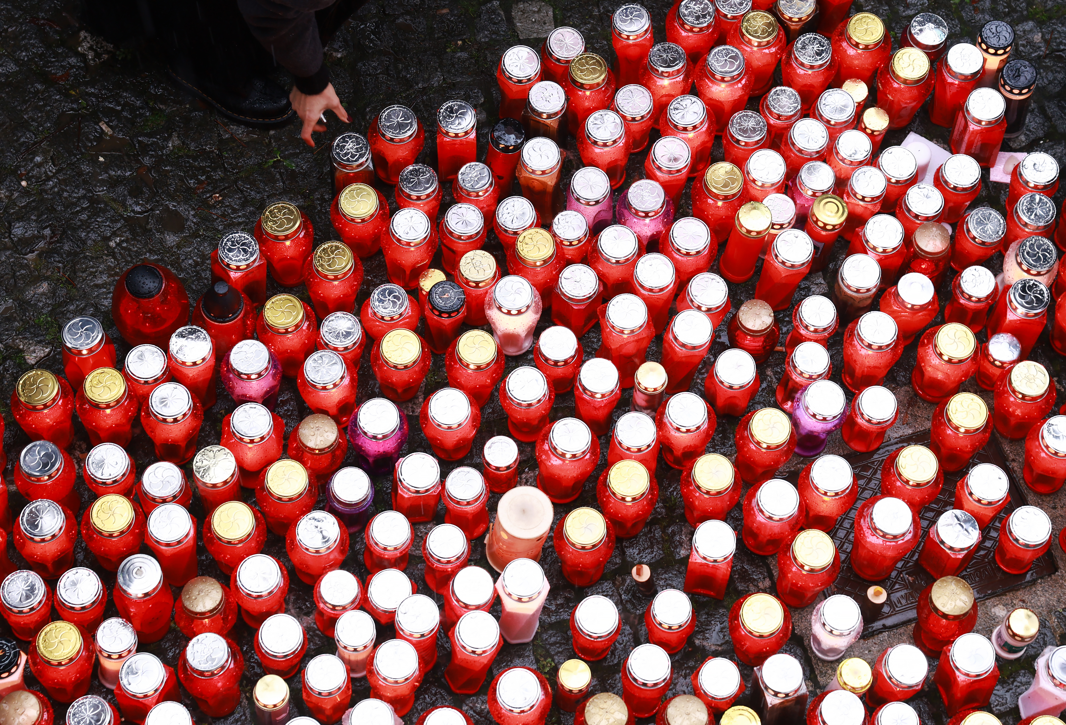 Ljudje prižigajo sveče v spomin moškega ki je umrl pred lokalom Lokalpatriot