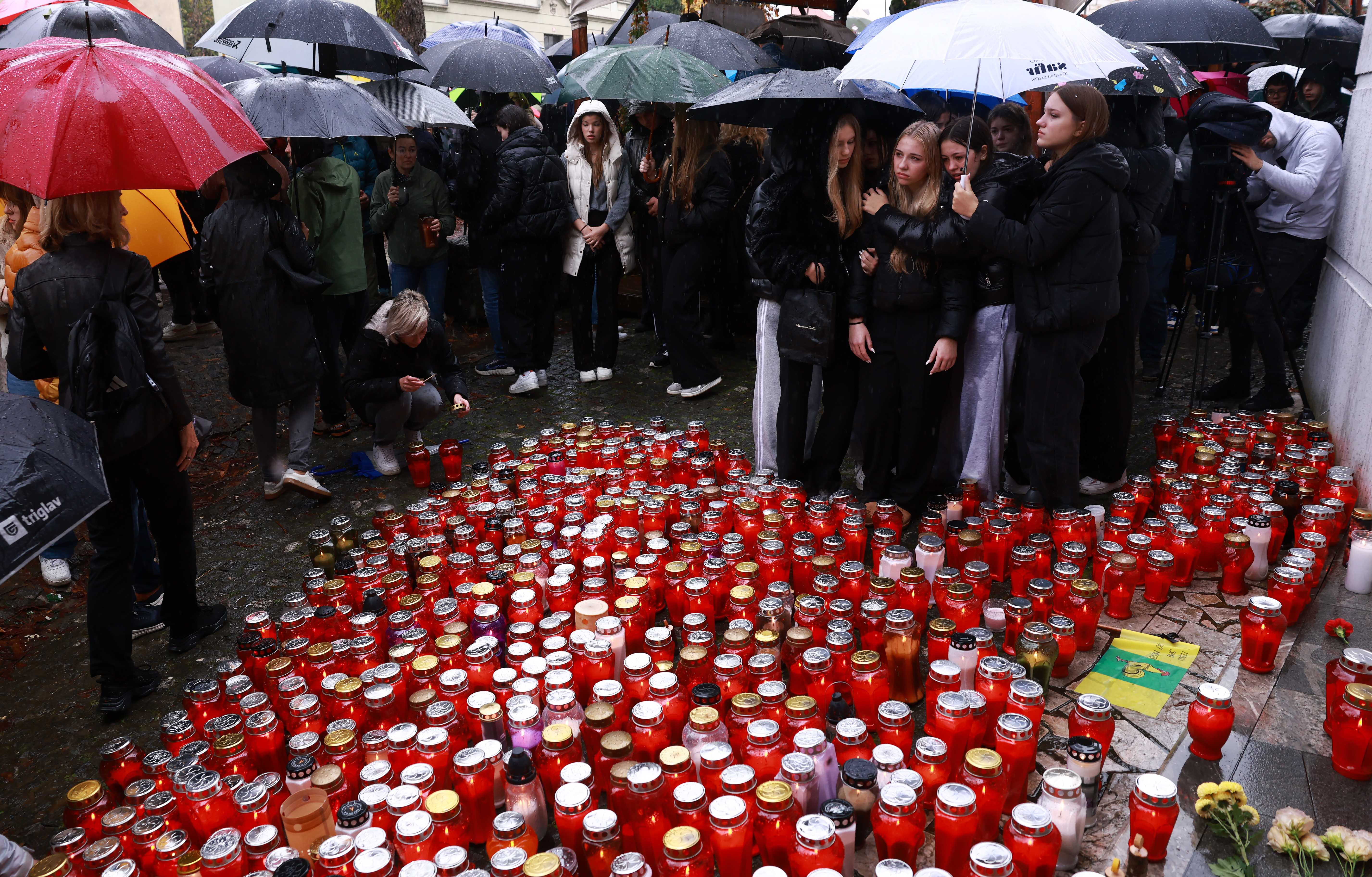Ljudje prižigajo sveče v spomin moškega ki je umrl pred lokalom Lokalpatriot