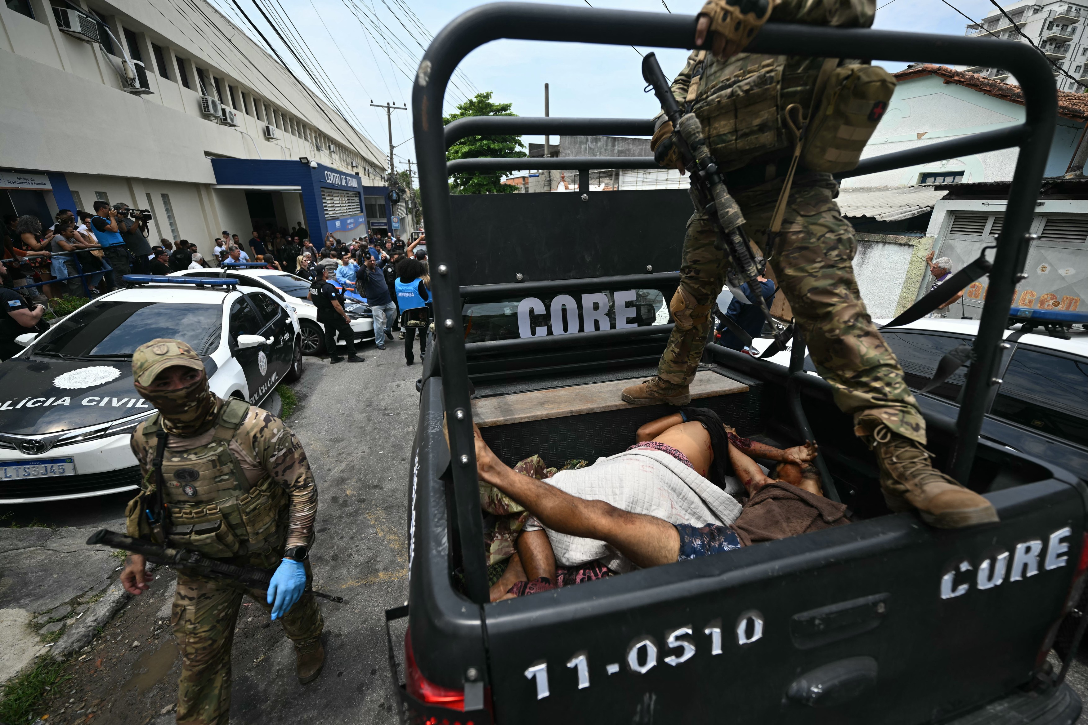 Police transport bodies to a hospital following Operacao Contencao