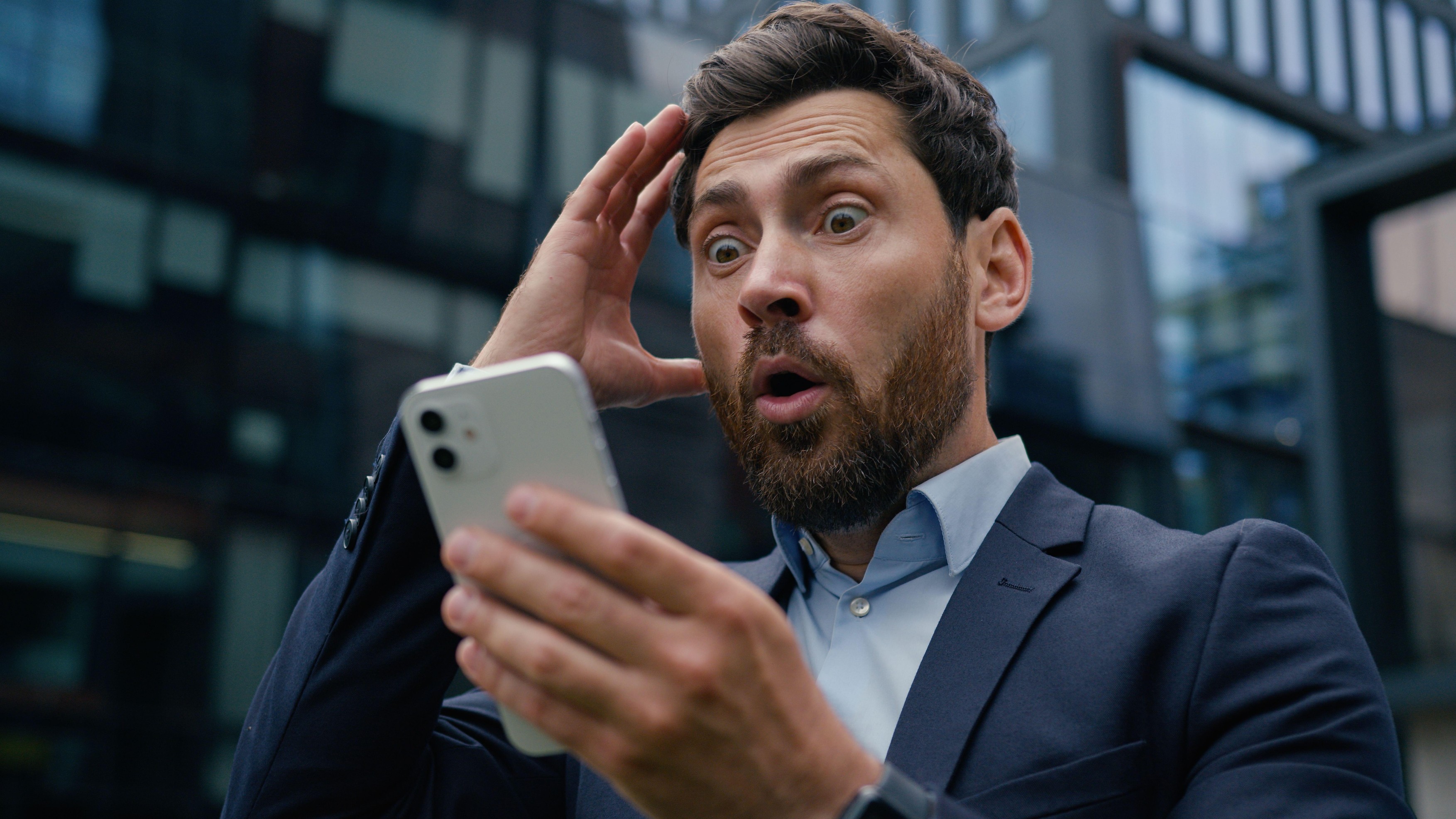 moški presenečen ob pogledu na ekran mobilnega telefona