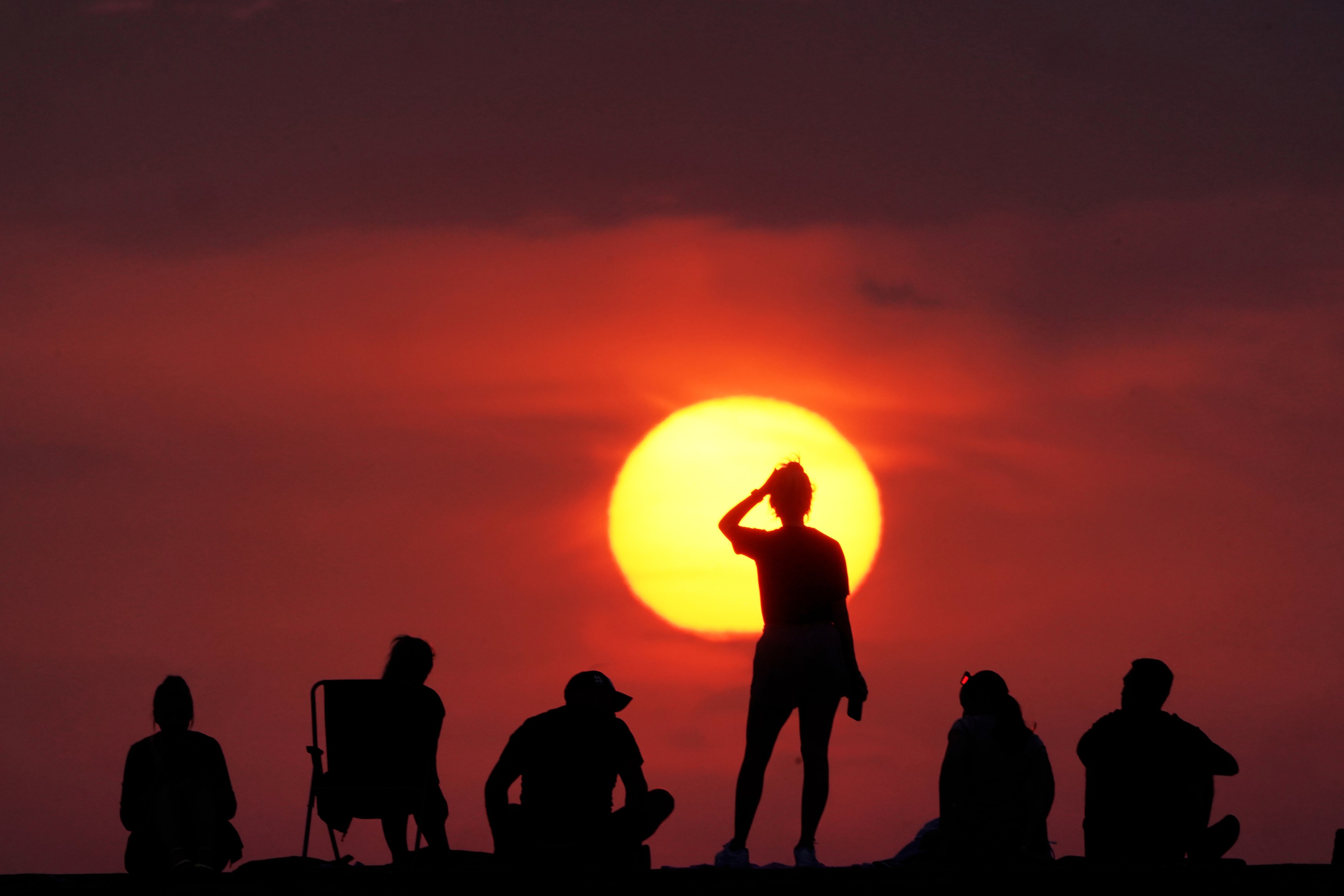 19/07/22 of people watching the sunrise at Cullercoats Bay, North Tyneside