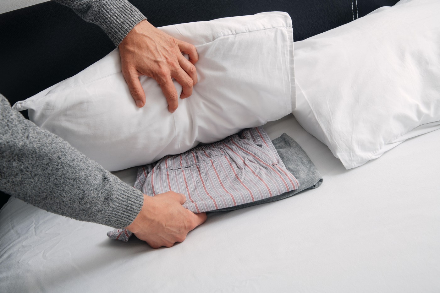 moški, ki daje svojo pižamo pod blazino