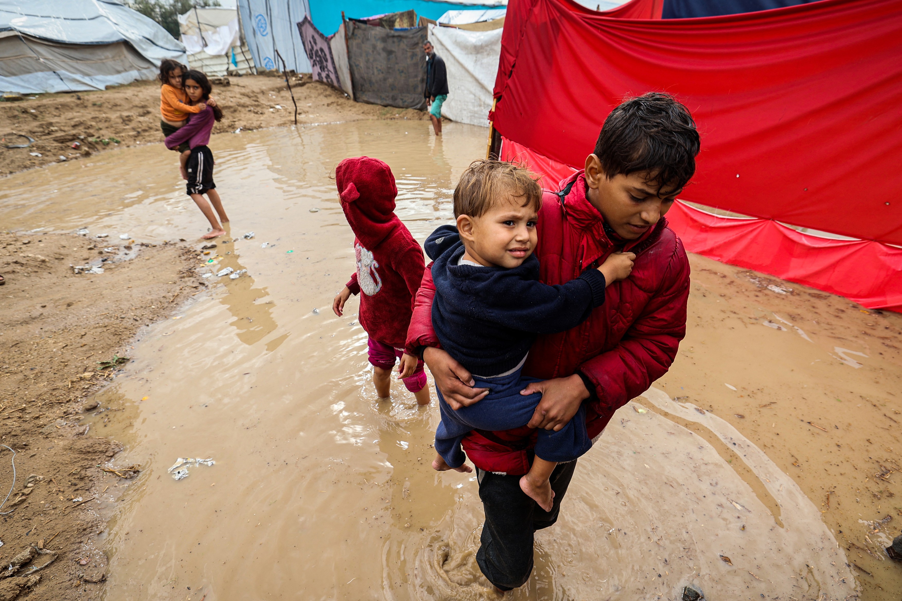 Palestinian children walk in flood water after heavy rain Maghazi refugee camp i November 25, 2025.