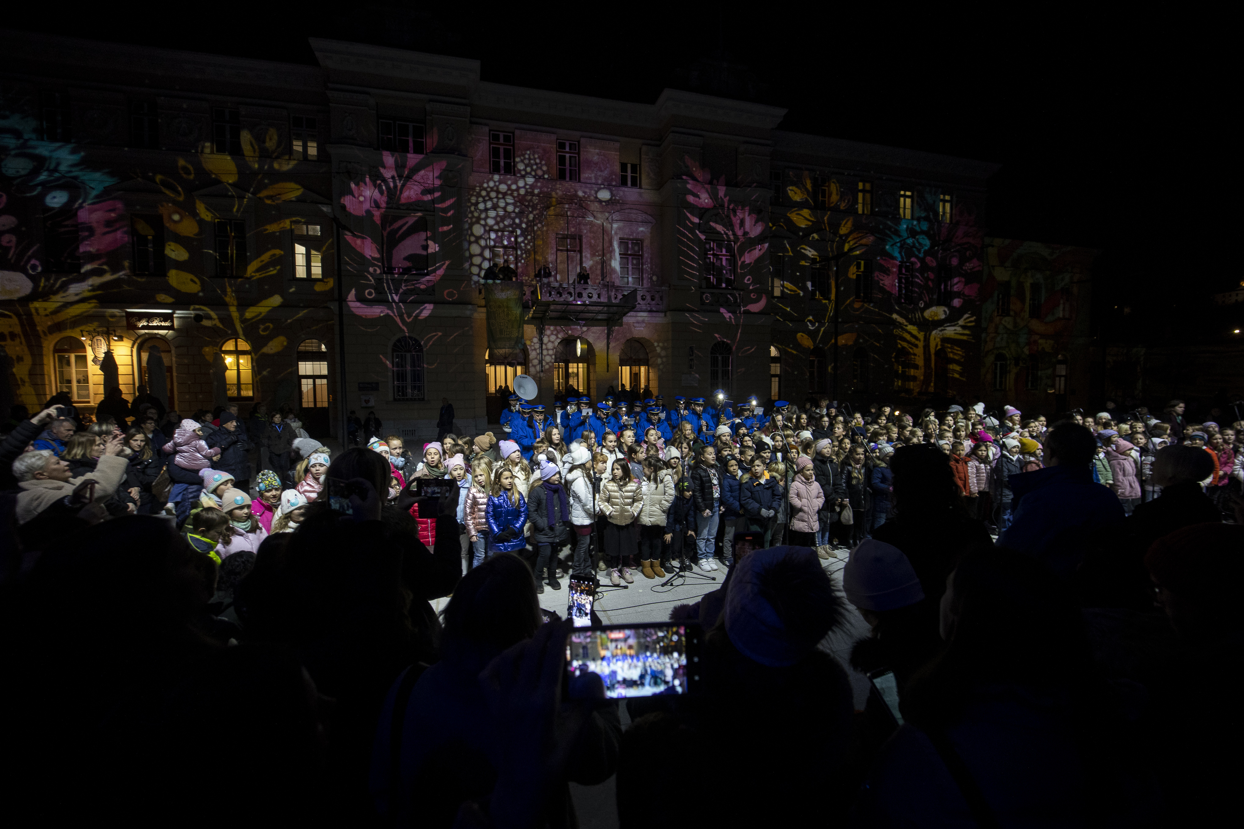 Slovenska in italijanska parada sta si podali vsaka s svoje strani meje ter se srecali na Trgu Evrope, kjer je svetloba simbolicno povezala obe mesti ter poudarila sporocilo.