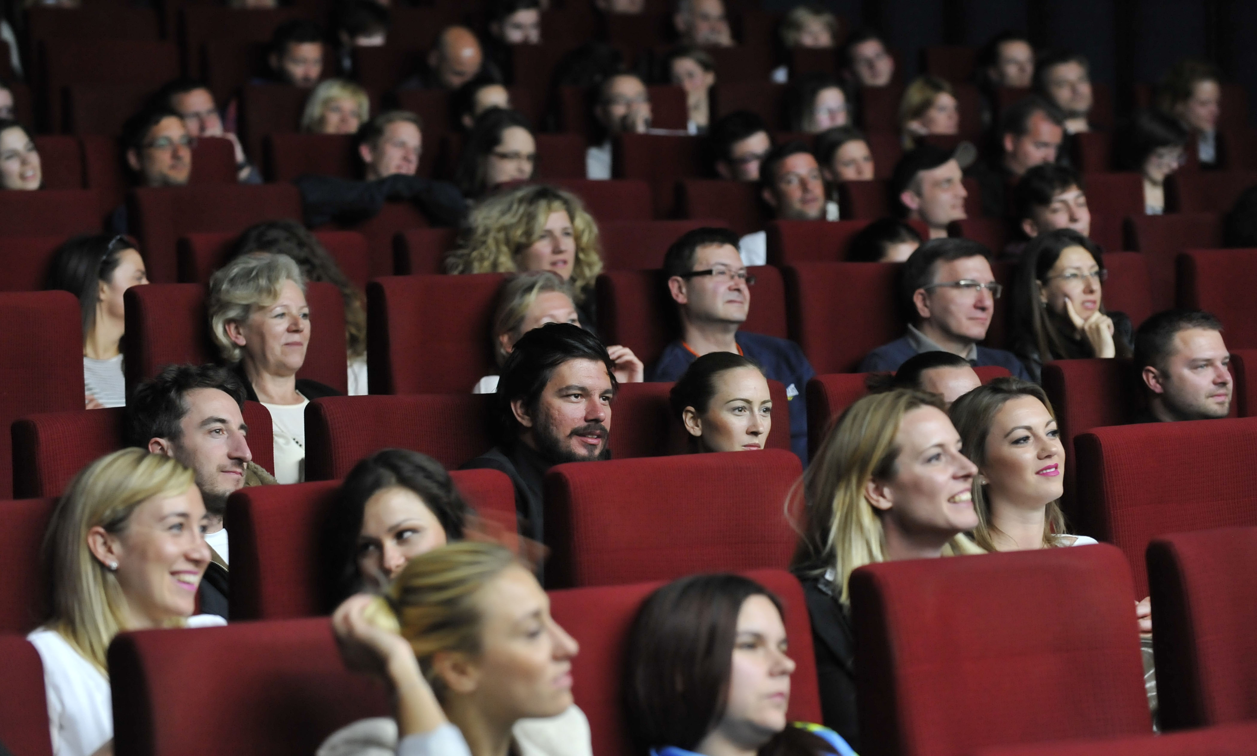 Ljudje sedijo v kinodvorani in gledajo film