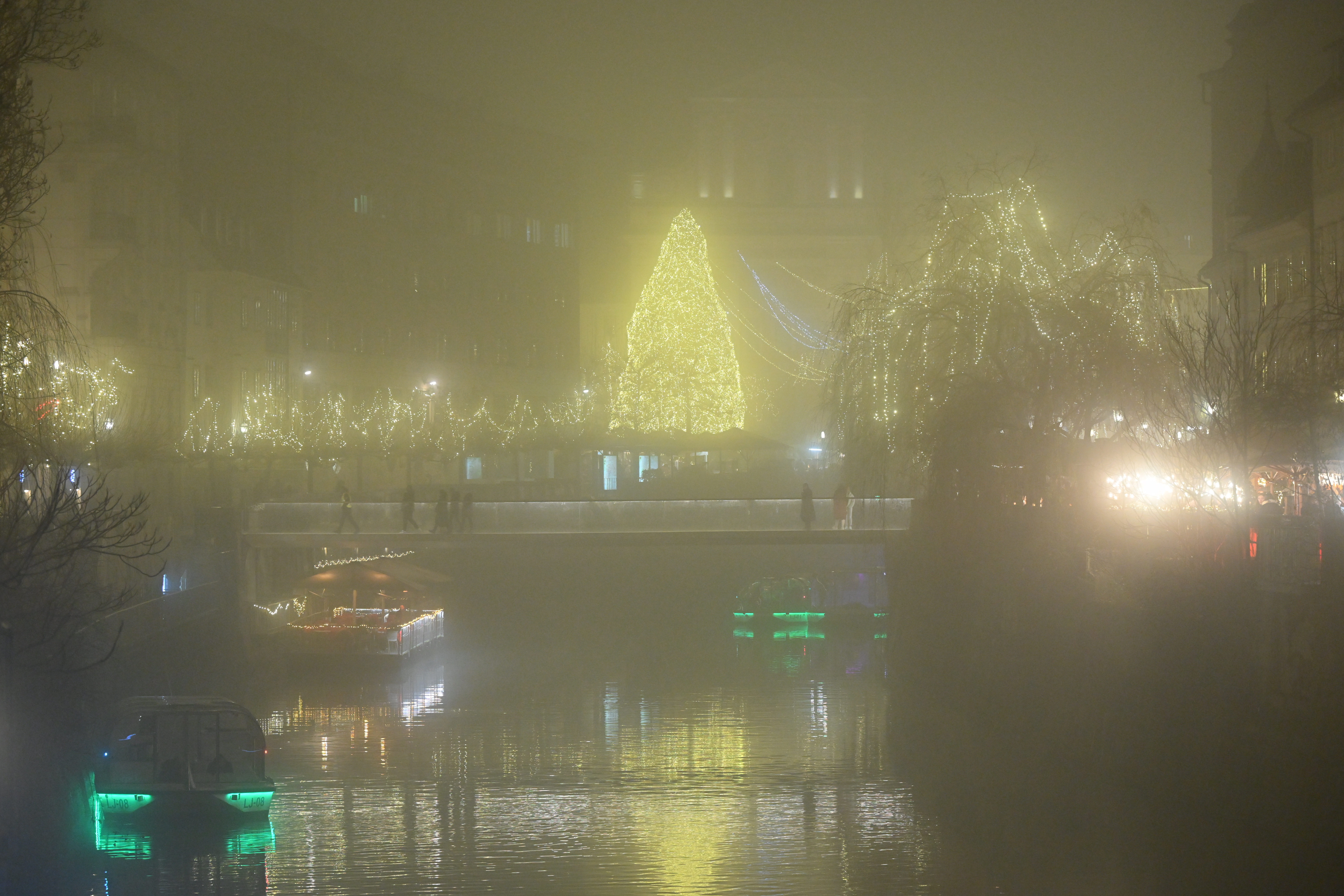 Slovenija, Ljubljana ,  16.12.2025, 16. december 2025 Novoletno vzdušje v starem delu meglene Ljubljane. Ljubljanica, ladjice, okrašeno mesto, hiške s ponudbo, lučke, megla , turizem,Novo leto Živulović jr/F.A.BOBO
