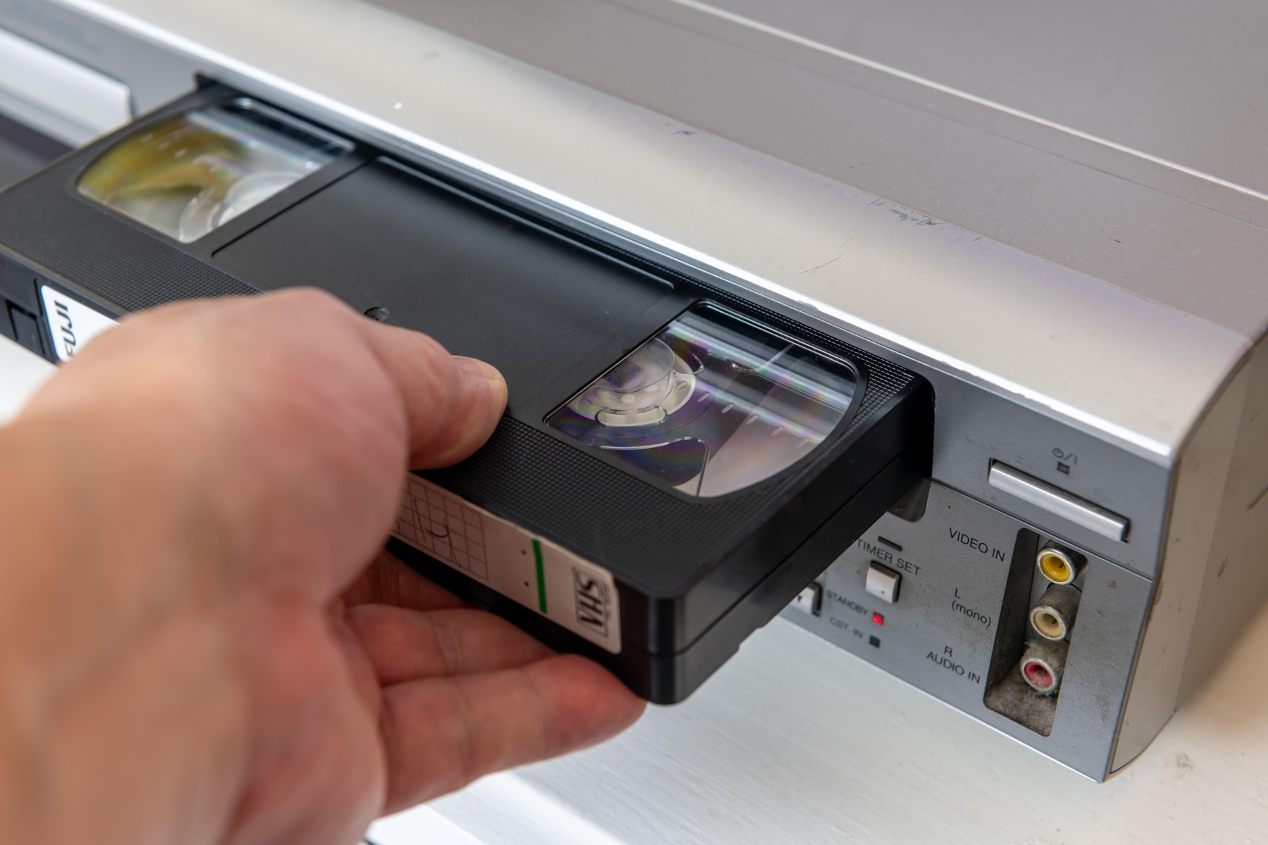 London. UK- 09.18.2024. A person inserting a video cassette into a vintage video player.